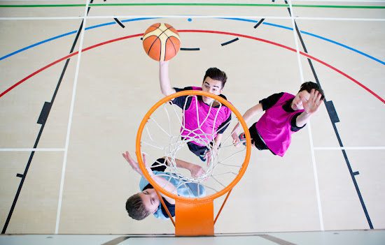 A few kids playing basketball inside a gym