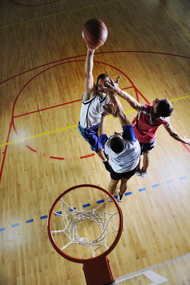 Guys playing basketball inside a gym