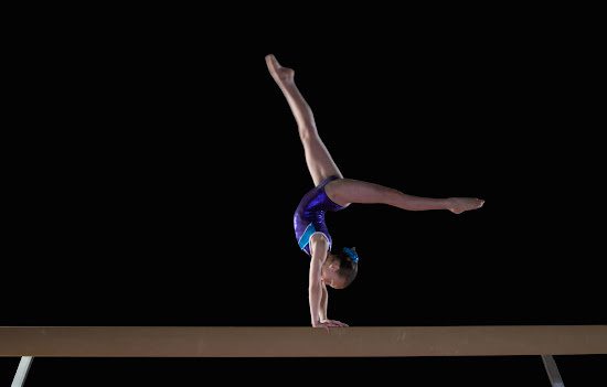 Girl doing handstand on balance beam