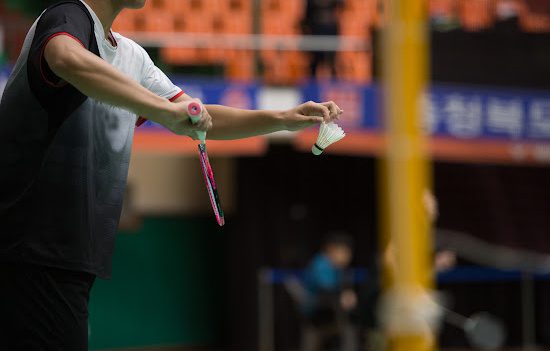 Person serving a shuttlecock during a badminton match