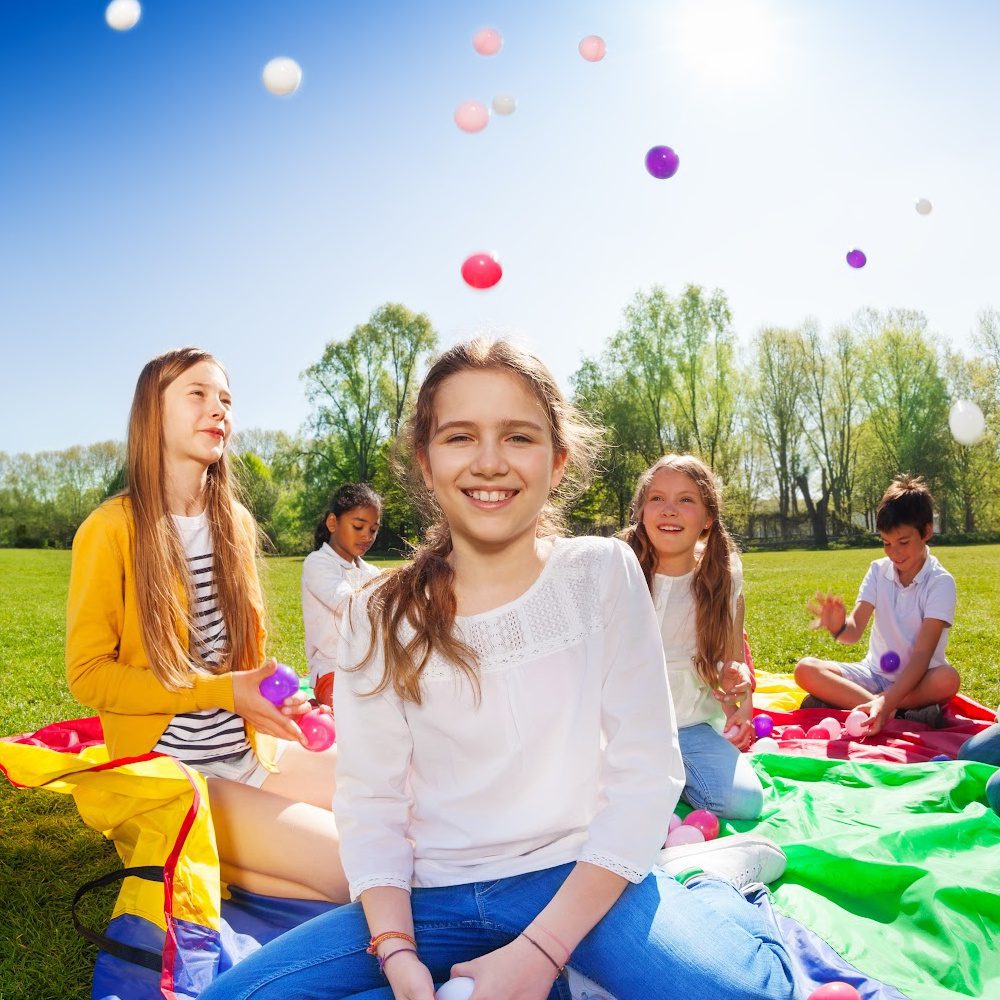 Kids sitting on a blanket playing with balloons at summer camp